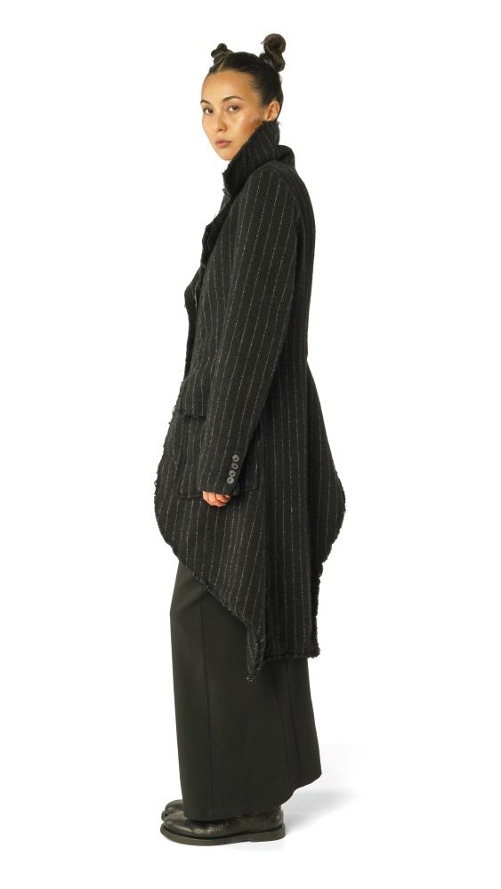 Frau trägt eleganten, schwarzen gestreiften Mantel mit weitem Schnitt und schwarzen Hosen.