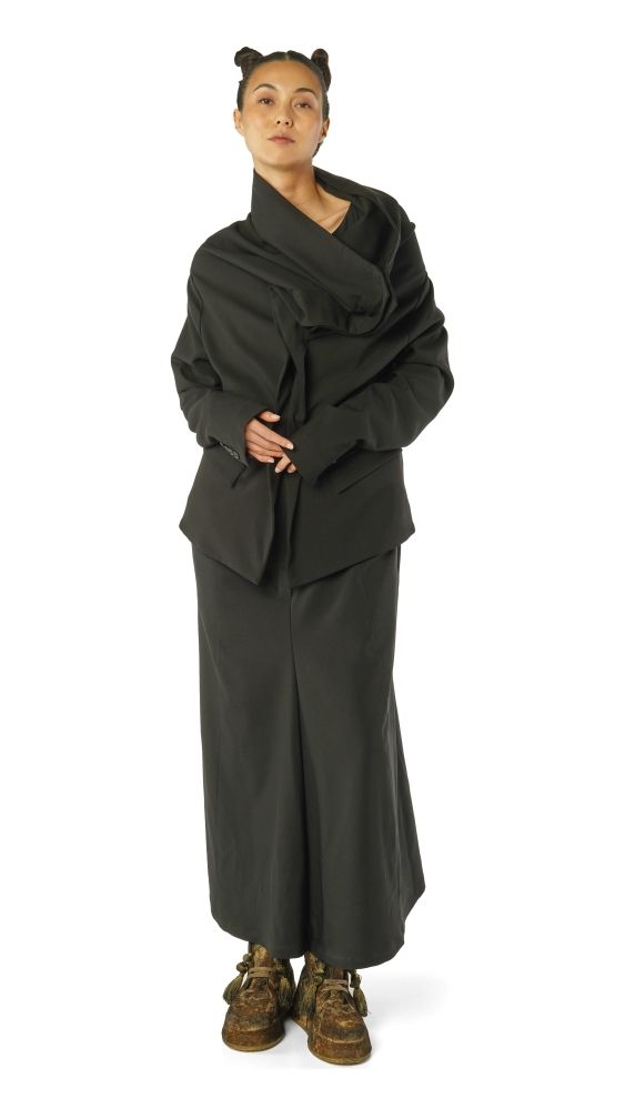 Person trägt langes schwarzes Cape-Kleid mit oversized Jacke, hohe Stiefel, Haare zu zwei Hörnern.