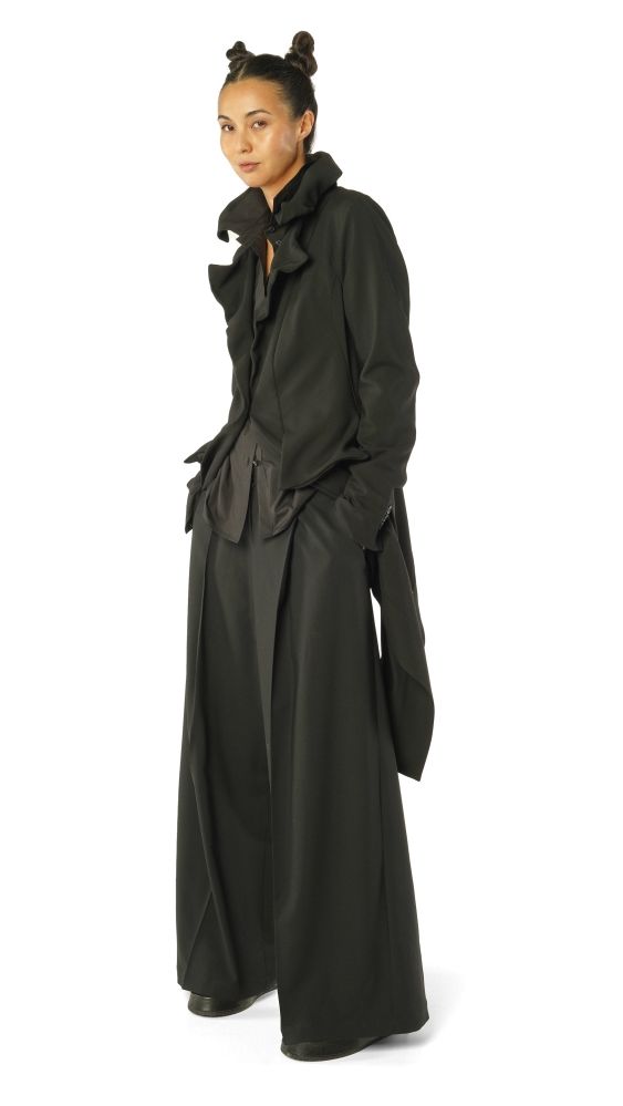 Moderne Frau trägt eleganten, langen schwarzen Mantel mit weiten Ärmeln und asymmetrischen Details.