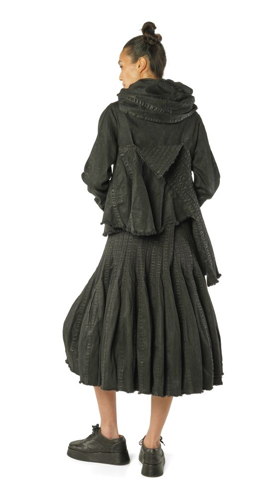 Frau trägt oversized schwarzen Strickmantel mit weitem Rock und Schal, schwarze Sneakers.