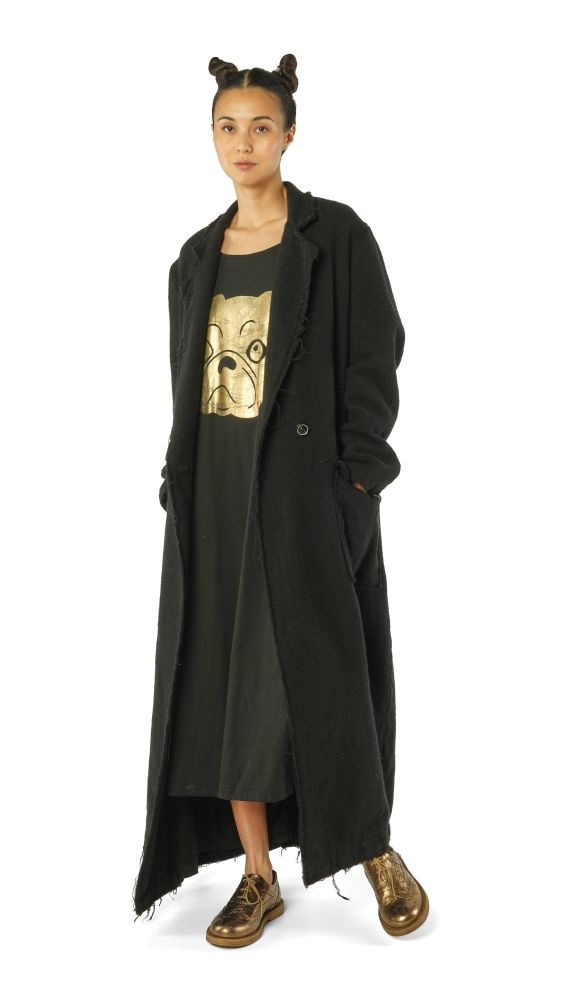 Frau trägt langen schwarzen Mantel mit goldener Katzen-T-Shirt-Illustration und goldenen Stiefeln.