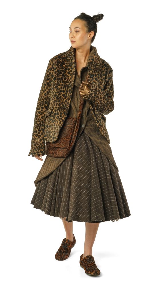 Frau trägt eleganten Leopardenmantel mit weitem Rock und passenden Schuhen, hält Handtasche.