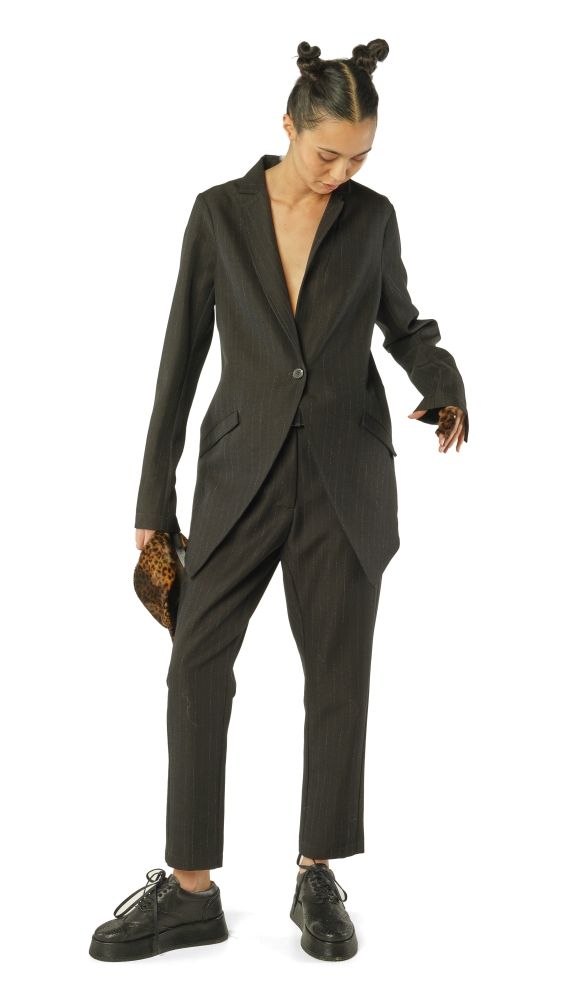Stylische Person in schwarzem Pinstripe-Anzug mit Bubble-Sneakern und Handtasche.