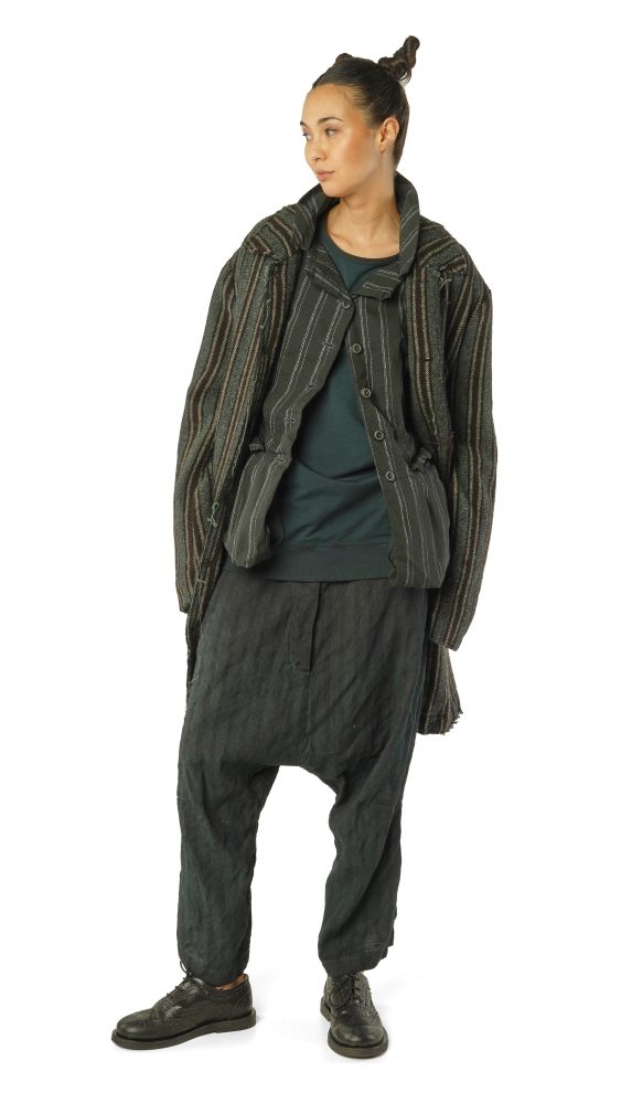 Person trägt oversized gestreiften Cardigan, dunkle Haremhose und Sneaker, mit dunklem Top.