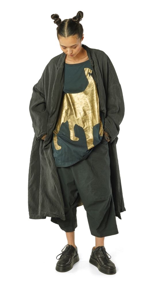 Person trägt oversized schwarzes Ensemble mit goldener Stickerei, hochgebundene Haare, bequeme Schuhe.