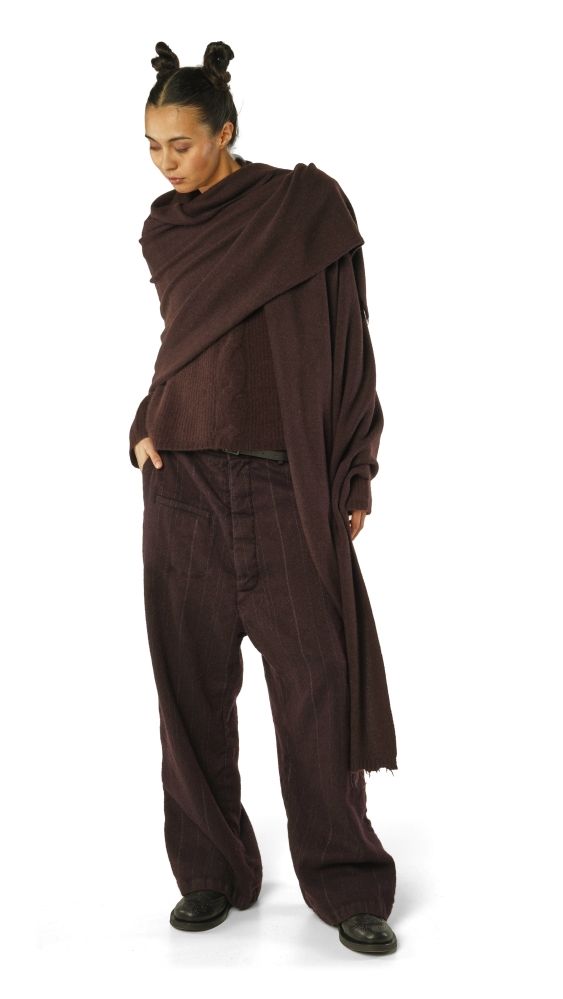 Person trägt maronenfarbene, weite Jumpsuit-Kombi mit langem Umhänge-Schal und Bumhaar-Frisur.