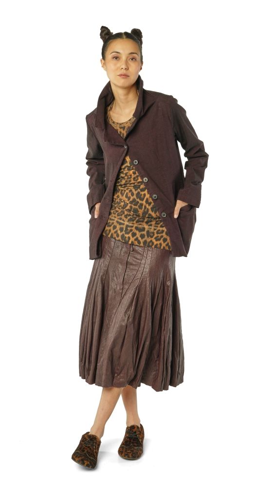 Frau trägt bunte, kreative Mischung aus Lederrock, leopardbedrucktem Top und braunem Mantel mit Accessoires.