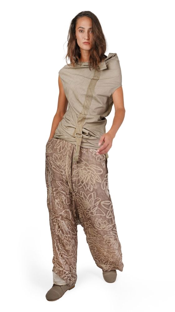 Frau trägt beige, gemusterte Jumpsuit-Kombi mit weitem Oberteil und weiten Hosen, Accessoires mit Gürtel.