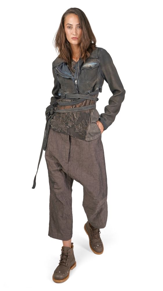 Stylische Person in oversized Jacke, weiten Haremhosen und robusten Stiefeln mit Gürtel und Tasche.