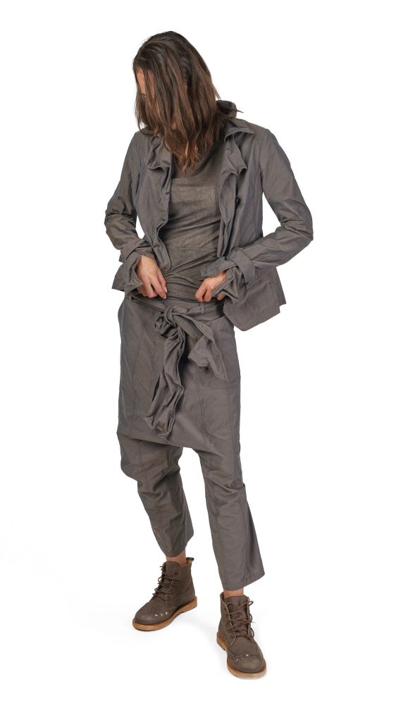 Person trägt graue oversized Jacke, weiten Jumper und harlem-pants mit robusten Schuhen.